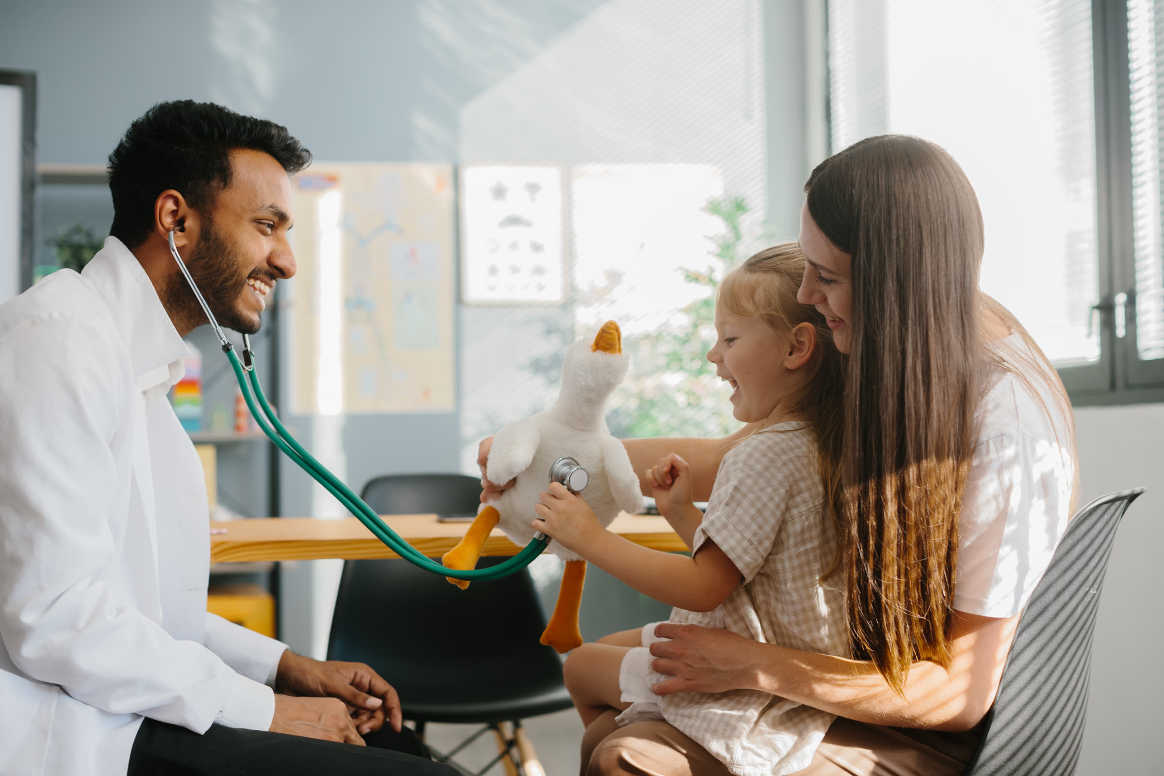 Child playfully examining a stuffed animal like a doctor